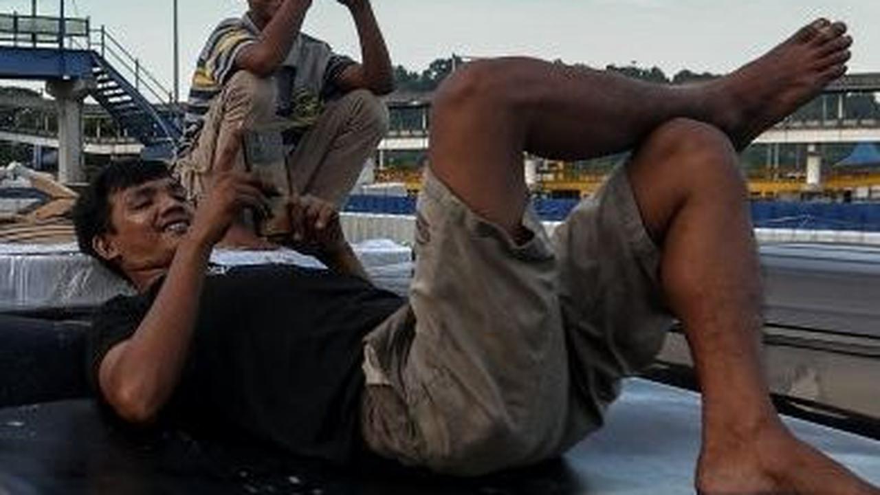Seorang pemudik bermain dengan gadgetnya saat menikmati antrean panjang di Pelabuhan Merak ketika bersantai di atap mobilnya. Foto: liputan6.com / Angga Yuniar