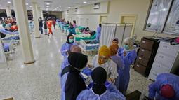 Staf medis berbicara di bangsal untuk pasien yang dirawat dalam wabah kolera Vibrio di aula masjid yang diubah menjadi rumah sakit lapangan di Kota Bebnine, Distrik Akkar, Lebanon Utara, Rabu (26/10/2022). Pada 13 Oktober, total 18 kasus telah dikonfirmasi, termasuk dua kemungkinan kematian. (AFP/Ibrahim Chalhoub)