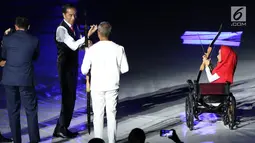 Presiden RI, Joko Widodo (tengah) bersiap memanah tugu bersama penyandang disabilitas saat malam pembukaan Asian Para Games 2018 di SUGBK, Jakarta, Sabtu (6/10).  Asian Para Games 2018 berlangsung 6-13 Oktober. (Liputan6.com/Helmi Fithriansyah)