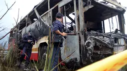 Petugas menginvestigasi bus pariwisata berisi wisatawan dari China daratan yang terbakar di dekat ibu kota Taiwan, Selasa (19/7). Bus yang dalam perjalanan ke bandara itu menabrak pagar jalan raya dan terbakar hingga menewaskan 26 orang. (Sam YEH/AFP)