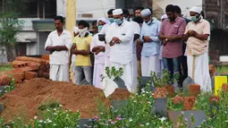 Keluarga dan kerabat memakai masker saat berdoa setelah penguburan jenazah yang tewas akibat terjangkit virus Nipah di Kozhikode, Kerala, India Selatan, Kamis (24/5). Wabah virus Nipah dimulai awal bulan ini di Kerala. (AP Photo/K.Shijith)
