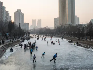 Sejumlah warga tampak menikmat bermain ice skating atau seluncur es di atas sungai yang telah membeku di Beijing, Jumat (1/1). Semenjak membeku, sungai di Beijing ini menjadi objek wisata es dadakan yang banyak diminati wisatawan.  (AFP/Fred Dufour) 