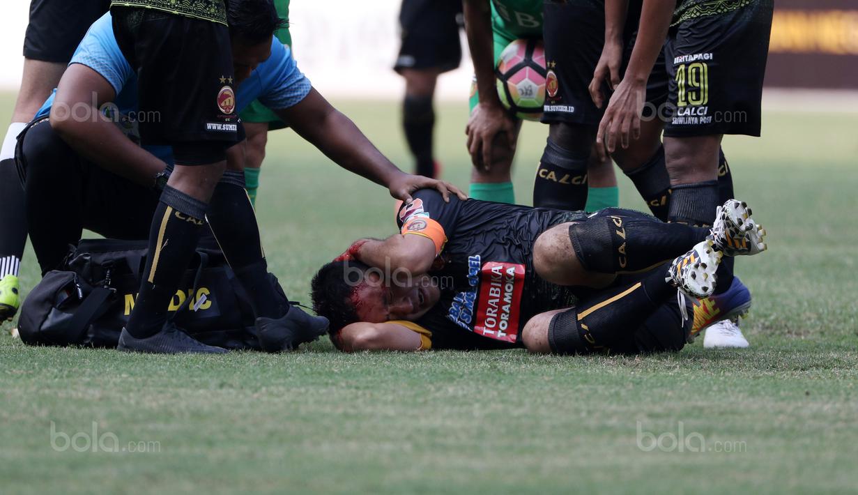 Pemain Sriwijaya FC, Yu Hyun-koo tergelatak usai berbenturan dengan pemain Bhayangkara FC pada lanjutan Liga 1 2017 di Stadion Patriot Bekasi, Minggu (20/8/2017). (Bola.com/Nicklas Hanoatubun)