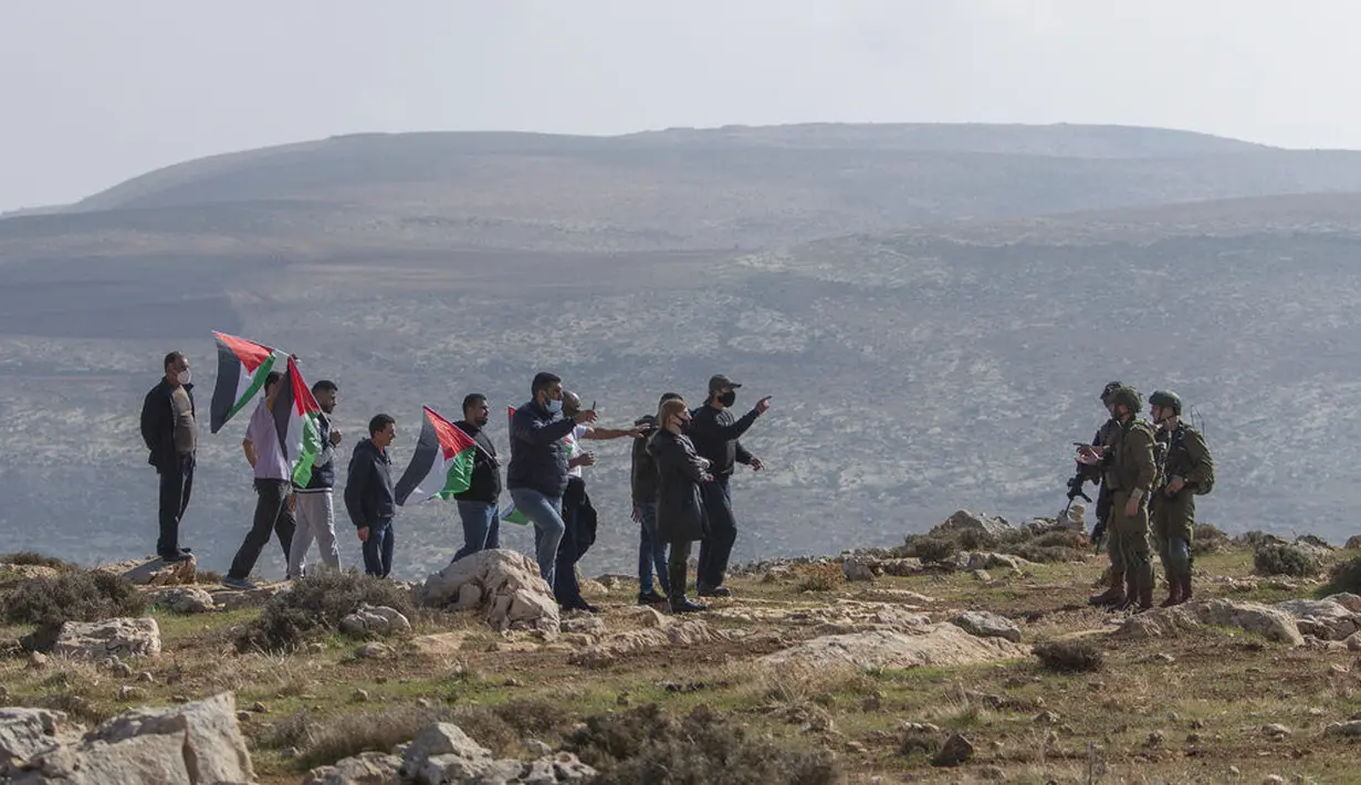Tentara Israel menghentikan pengunjuk rasa Palestina untuk mencapai pos pemukiman Yahudi di Desa Mughayer, Ramallah, Tepi Barat, Jumat (18/12/2020). Pengunjuk rasa Palestina yang menggunakan ketapel terlibat bentrok dengan pemukim Yahudi yang menggunakan anjing. (AP Photo/Nasser Nasser)