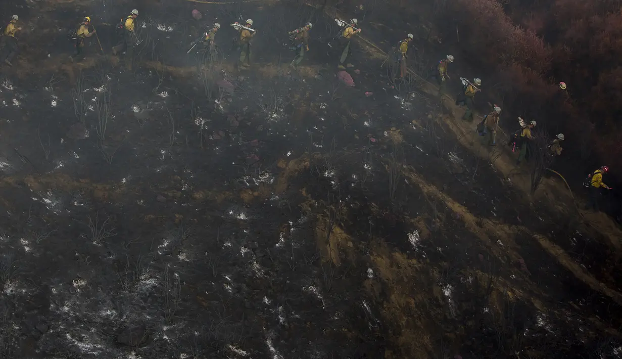 Petugas pemadam kebakaran berbaris untuk bekerja pada hot spot yang tersisa dari kebakaran hutan yang disebut Apple Fire di dekatnya di Cherry Valley, California (1/8/2020). California merupakan salah satu daerah paling rawan kebakaran. (AP Photo/Ringo H.W. Chiu)