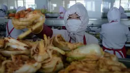 Dalam foto pada 1 Desember 2020, pekerja menyortir kubis di lini produksi pembuatan kimchi di Pabrik Kimchi Ryugyong di Pyongyang, Korea Utara. Setiap tahunnya, pabrik itu menghasilkan sekitar 4.200 ton acar khas Korea yang terbuat dari sayuran kubis yang diawetkan tersebut. (KIM Won Jin/AFP)
