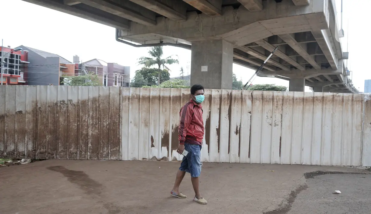 Warga berada di balik pagar pembatas yang menutup akses menuju kawasan Cipinang Melayu, Jakarta, Minggu (29/3/2020). Warga membatasi aktivitas pengunjung yang melintasi kawasan mereka dengan menutup sebagian jalan dengan seng guna mengantisipasi penyebaran corona Covid-19 (merdeka.com/Iqbal Nugroho)