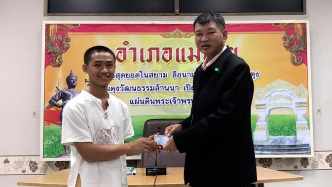 Salah seorang remaja, Adul Samon menerima kartu identitas sebagai warga negara Thailand di distrik Mae Sai, Rabu (8/8). Korban gua Thailand tersebut selama ini hidup tanpa memiliki status kewarganegaraan. (Chiang Rai Public Relations Office via AP)