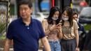 Dua perempuan melihat smartphone saat mereka berdiri di sudut jalan di Beijing, Rabu (6/7/2022). Warga beberapa bagian Shanghai dan Beijing telah diperintahkan untuk menjalani tes massal COVID-19 lebih lanjut menyusul ditemukannya kasus baru di dua kota, sementara pembatasan tambahan tetap berlaku di Hong Kong, Makau, dan kota-kota lain. (AP Photo/Mark Schiefelbein)