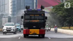 Puluhan personel serta kendaraan dinas operasional gabungan Pemprov DKI Jakarta dan Polda Metro Jaya melakukan penyiraman di kedua sisi sepanjang Jalan Sudirman-Thamrin. (Liputan6.com/Angga Yuniar)