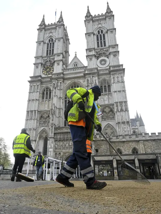 Orang-orang bekerja saat menyiapkan lahan di depan Westminster Abbey pada hari upacara penobatan Raja Charles III  di London, Sabtu (6/5/2023). (Toby Melville/Pool Photo via AP)