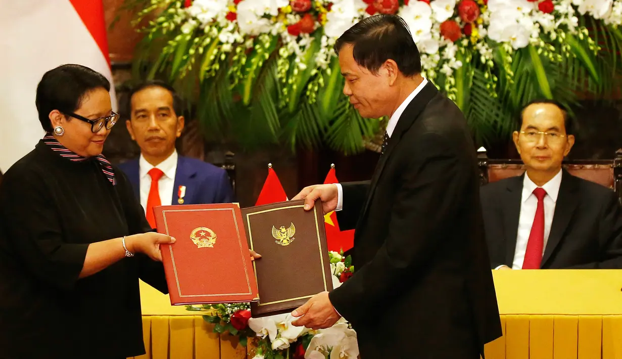 Presiden Joko Widodo menyaksikan Menteri Luar Negeri Retno Marsudi bertukar dokumen dengan Menteri Pertanian Vietnam Nguyen Xuan Cuong setelah upacara penyambutan di Istana Kepresidenan, Hanoi, Vietnam (11/9). (AP Photo/Bullit Marquez)