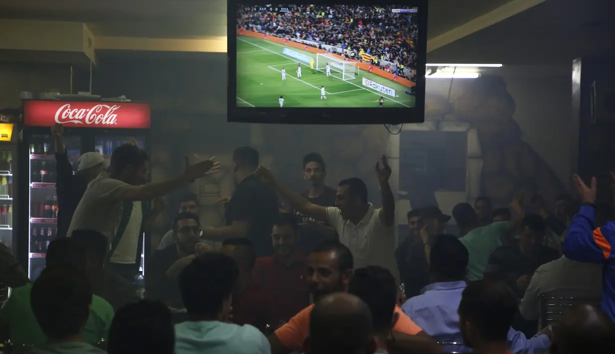 Warga Palestina menyaksikan pertandingan sepak bola El Clasico antara Real Madrid dan Barcelona FC di sebuah kafe di kota Ramallah, Tepi Barat (6/5). Real Madrid dan Barcelona meraih hasil imbang 2-2 di pertandingan tersebut. (AFP Photo/Abbas Momani)
