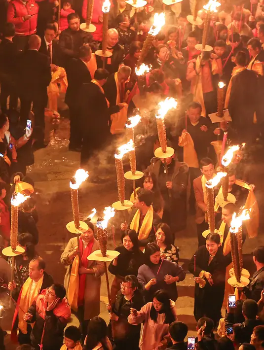Warga berdoa sambil memegang obor saat mengikuti parade pada sebuah festival obor di Jinjiang di provinsi Fujian, China timur (24/2). Ratusan warga China mengikuti parade obor untuk keberhasilan di tahun yang baru. (AFP Photo)