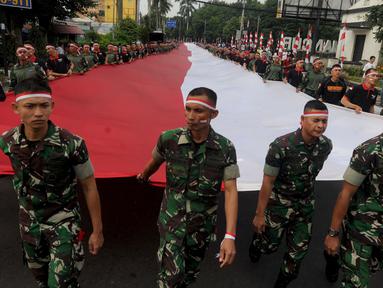 Anggota TNI POLRI  membawa bendera raksasa saat gelaran Festival Merah-Putih (FMP) 2018 di kawasan Air Mancur, Bogor,  Minggu (5/8). Bendera tersebut berukuran panjang 117 meter dan lebar 5 meter. (Merdeka.com/Arie Basuki)