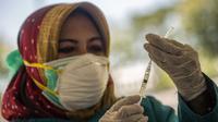 Seorang dokter bersiap untuk memberikan vaksin virus corona COVID-19 Sinovac di klinik vaksinasi massal darurat di lapangan sepak bola di Surabaya, Jawa Timur, Selasa (6/7/2021). Indonesia tengah memerangi gelombang infeksi baru yang belum pernah terjadi sebelumnya. (JUNI KRISWANTO/AFP)