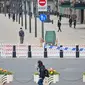 Orang-orang berjalan di sekitar Bund, sepanjang Sungai Huangpu, Puxi, Shanghai, 31 Maret 2022. Daerah Puxi akan lockdown mulai 1 April 2022. (Hector RETAMAL/AFP)