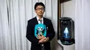 Akihiko Kondo asal Jepang berpose di sebelah hologram aktris virtual, Hatsune Miku sambil memegang versi bonekanya di Tokyo, 10 November 2018. Kondo memutuskan menikahi boneka karena mengalami kesulitan berinteraksi di tempat kerjanya. (Behrouz MEHRI/AFP)