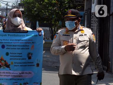 Petugas Satpol PP membentangkan spanduk saat melakukan sosialisasi kepada warga terkait polusi udara di Kelurahan Cipinang, Jakarta, Jumat (22/9/2023). Kegiatan ini dilakukan untuk mengimbau warga agar mengenakan masker saat beraktivitas di luar ruangan dan tidak membakar sampah karena tingkat polusi udara Jakarta semakin parah. (merdeka.com/Imam Buhori)