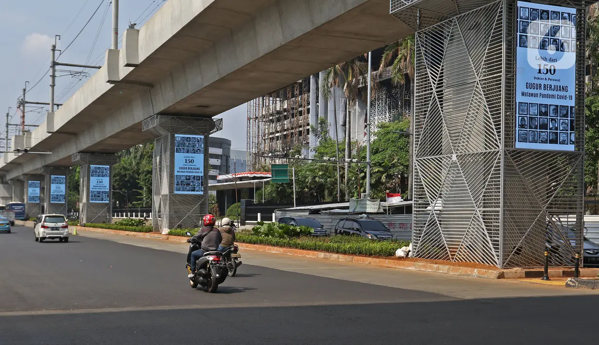 Pengendara melintasi videotron penghormatan kepada tenaga medis yang gugur akibat Covid-19 di tiang penyangga lintasan MRT, Jalan Sisingamangaraja, Jakarta, Jumat (18/9/2020). Keberadaan videotron tersebut diharap mampu membuat masyarakat waspada akan ancaman Covid-19. (Liputan6.com/Herman Zakharia)