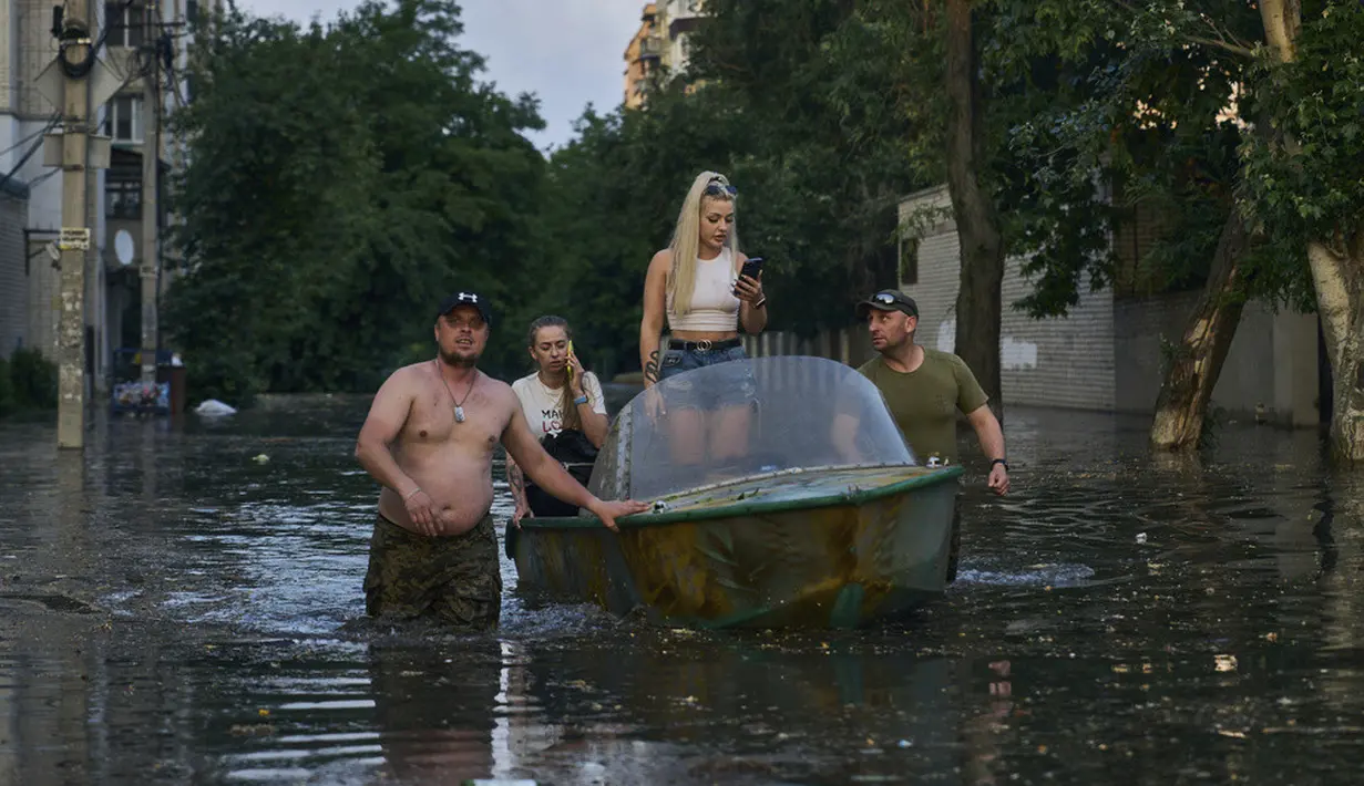 <p>Petugas penyelamat berusaha menarik perahu yang membawa penduduk yang dievakuasi dari lingkungan banjir di Kherson, Ukraina, Selasa (6/6/2023). Tembok bendungan besar di bagian selatan Ukraina telah runtuh, memicu banjir, membahayakan pembangkit listrik tenaga nuklir terbesar di Eropa dan mengancam persediaan air minum. (AP Photo/Libkos)</p>