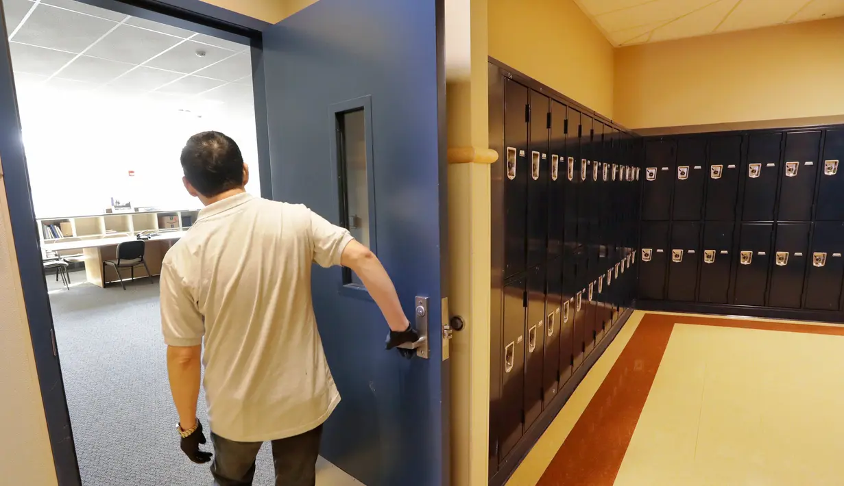 Petugas kebersihan membuka pintu ruang staf di Bothell High School yang ditutup di Bothell, Washington, Kamis (27/2/2020). Sekolah di pinggiran kota Seattle ditutup setelah  anggota keluarga seorang staf sekolah itu dikarantina karena menunjukkan gejala tertular virus corona. (AP/Elaine Thompson)