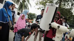 Pengunjung mengamati gerhana matahari cincin menggunakan teleskop di Planetarium Taman Ismail Marzuki, Jakarta, Kamis (26/12/2019). Planetarium menyediakan sekitar 10 teleskop dan kacamata khusus agar pengunjung bisa menyaksikan gerhana matahari cincin dengan aman. (Liputan6.com/Faizal Fanani)