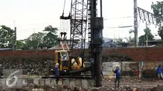 Pekerja menyelesaikan pekerjaannya di bantaran Kali Ciliwung, Bukit Duri, Jakarta (1/11). Pemasangan tiang pancang untuk sheet pile di kali tersebut telah mencapai 1300 meter, ditargetkan selesai akhir Desember 2016. (Liputan6.com/Gempur M Surya)