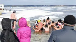 Orang-orang menyaksikan penggemar renang es di Danau Zalew Zegrzynski di Nieporet, Polandia, Minggu (25/2). Gelombang dingin sedang melanda Polandia. (AP Photo/Alik Keplicz)