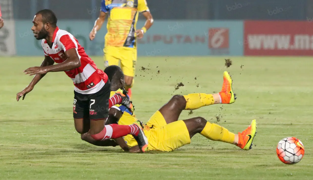 Pemain Madura United, Engelberd Sani (kiri) dihadangan pemain Persiba Balikpapan, Dirkir Gohn Glay pada laga Torabika SC 2016 di Stadion Gelora Bangkalan, Senin(13/6/2016).  (Bola.com/Nicklas Hanoatubun)