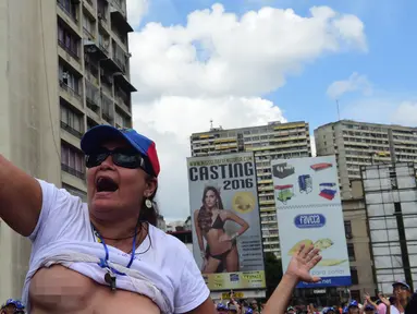 Seorang wanita membuka kausnya saat berunjuk rasa menentang Presiden Venezuela Nicolas Maduro di Caracas, Sabtu (6/5). Aksi ini berlangsung di sebagian kota besar Venezuela dan merupakan kelanjutan untuk melawan Maduro. (AFP PHOTO / RONALDO SCHEMIDT)
