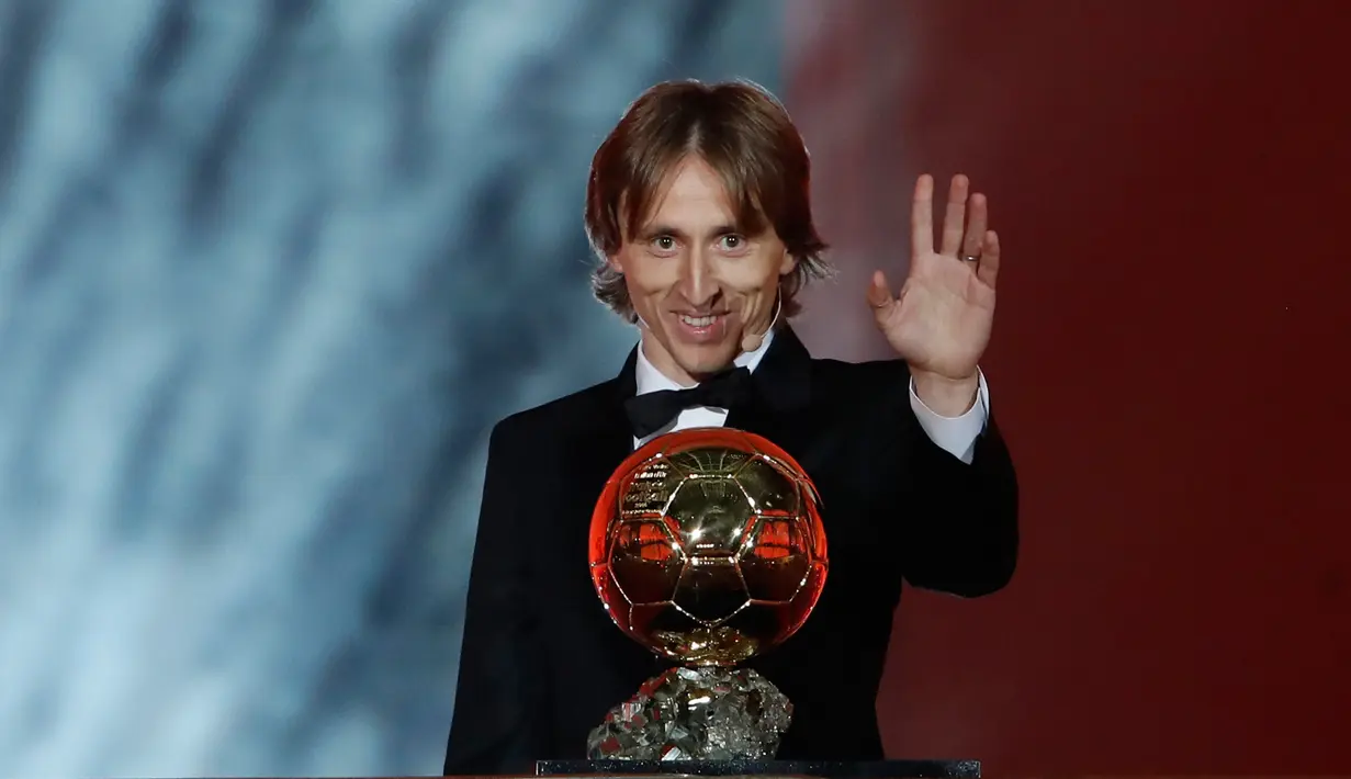 Gelandang Real Madrid, Luka Modric melambaikan tangan sambil memegang penghargaan Ballon d'Or 2018 di Grand Palais, Paris, Senin (3/12). Modric sukses memutus dominasi Cristiano Ronaldo dan Lionel Messi yang bertahan selama satu dekade (AP/Christophe Ena)