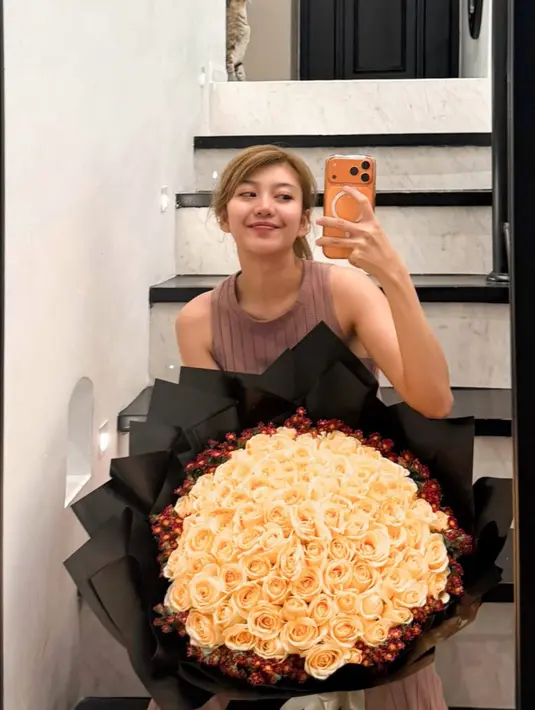 Dengan wajah tanpa makeup dan baju set coklat top sleeveless, Ghea Indrawari mendapatkan bunga buket mawar kuning yang besar. [@gheaindrawari]