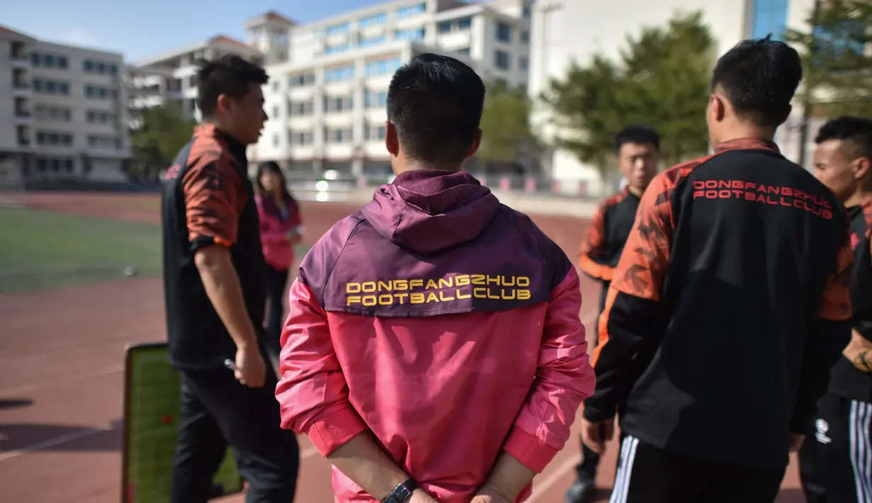 Mantan penyerang Manchester United, Dong Fangzhuo (kiri) berbicara dengan pelatih lain dari klub sepak bola Dong Fangzhuo, di Xiamen, Fujian, China (10/12/2019). Dong Fangzhuo yang kini berusia 34 tahun melatih anak-anak di China, beberapa di antaranya berkebutuhan khusus. (AFP/Hector Retamal)