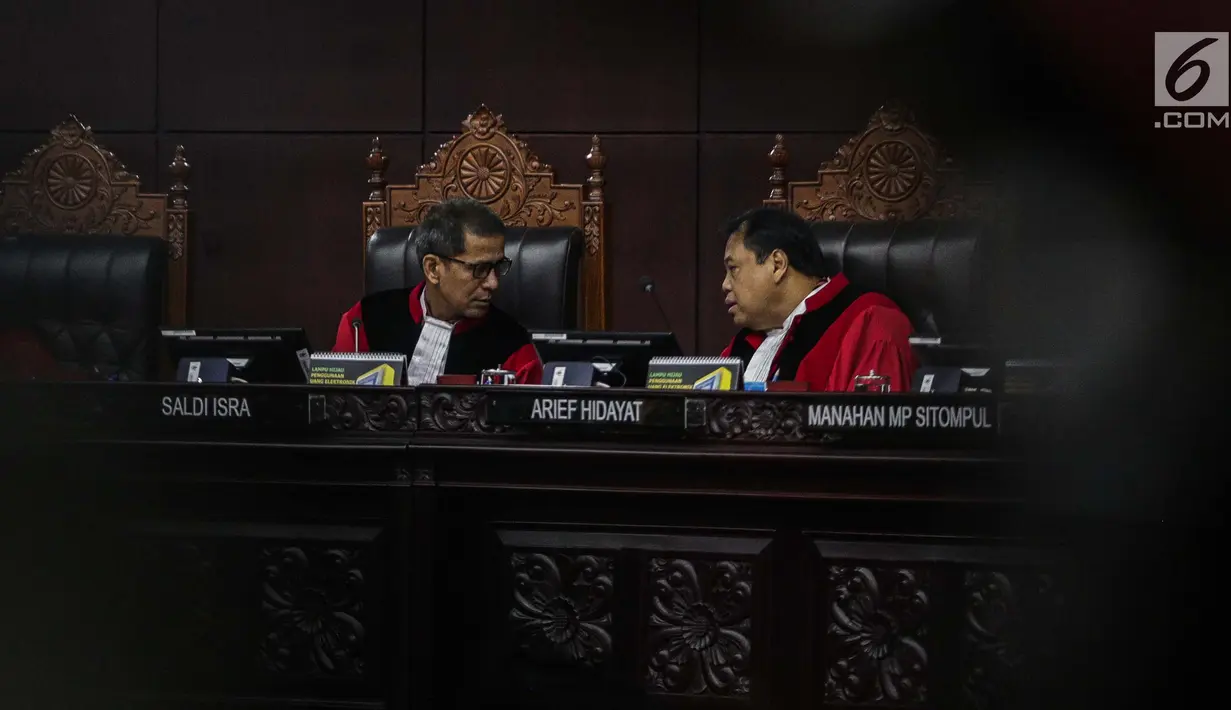 Hakim Konstitusi Arief Hidayat dan Saldi Isra berbincang disela pembukaan sidang putusan sengketa hasil Pilpres 2019 di Gedung Mahkamah Konstitusi, Jakarta, Kamis (27/6/2019). Sidang tersebut beragendakan pembacaan putusan oleh majelis hakim MK. (Liputan6.com/Faizal Fanani)