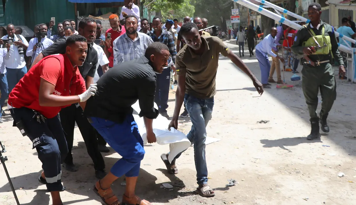 Petugas dibantu warga membawa jenazah korban di lokasi serangan bom mobil di Distrik Hamarwayne, Mogadishu, Somalia (4/2). Menurut Polisi setempat, serangan bom mobil tersebut meledak di dekat sebuah mal di pasar. (AFP Photo/Abdirazak Hussein Farah)