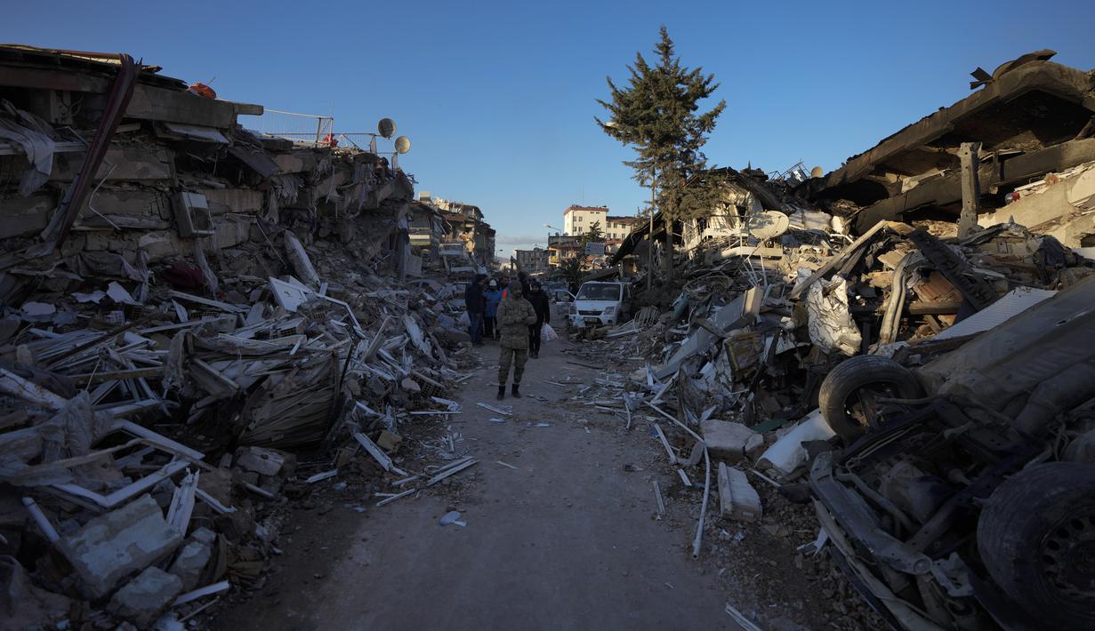 Seorang pria berjalan di tengah bangunan yang hancur di Antakya, Turki selatan, Rabu, 8 Februari 2023. Dengan harapan menemukan korban selamat memudar, tim penyelamat yang membentang di Turki dan Suriah pada Rabu masih mencari tanda-tanda kehidupan di antara puing-puing ribuan bangunan yang roboh akibat gempa paling mematikan di dunia dalam lebih dari satu dekade.  (AP Photo/Khalil Hamra)