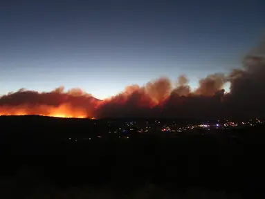 Kebakaran hutan yang membakar memancarkan cahaya di atas lingkungan di pinggiran Flagstaff, Arizona, Minggu (12/6/2022). Evakuasi telah diperintahkan untuk rumah-rumah di daerah tersebut. Pihak berwenang mengatakan petugas pemadam kebakaran menanggapi kebakaran hutan sekitar enam mil di utara Flagstaff yang telah memaksa evakuasi. (AP Photo/Felicia Fonseca)