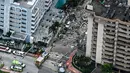 Pemandangan udara ini, menunjukkan tim penyelamat dan pencarian berada di lokasi runtuhnya sebagian menara apartemen tepi laut di Surfside, utara Miami, Kamis (24/6/2021). Tim tanggap menggunakan anjing dan drone terlatih untuk mencari korban selamat. (CHANDAN KHANNA/AFP)