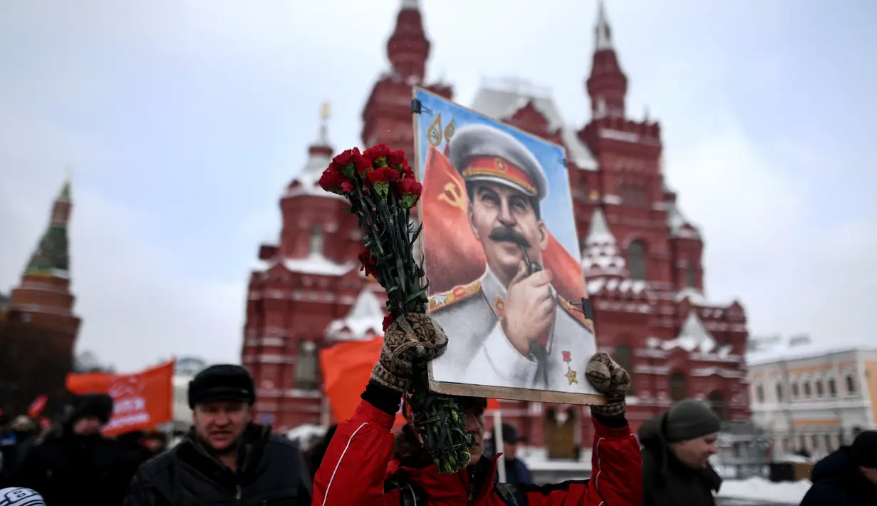 Seorang wanita membawa lukisan potret Stalin saat menghadiri upacara memperingati 65 tahun kematian pemimpin Uni Soviet Joseph Stalin di Lapangan Merah, Moskow (5/3). Stalin meninggal pada tahun 1924. (AFP/Kirill Kudryavtsev)