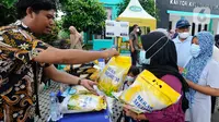 Petugas melayani warga yang membeli bahan kebutuhan pokok dengah harga di bawah harga eceran tertinggi (HET) saat kegiatan operasi pasar di Kantor Kelurahan Sawah, Tangerang Selatan, Banten, Kamis (29/9/2022). Dinas Perindustrian dan Perdagangan (Disperindag) Kota Tangerang Selatan menggelar operasi pasar di tujuh kecamatan dalam rangka penanganan inflasi sebagai dampak kenaikan harga bahan bakar minyak (BBM). (merdeka.com/Arie Basuki)