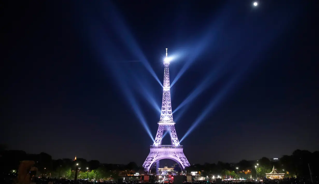 Pertunjukan cahaya menerangi Menara Eiffel saat perayaan ulang tahunnya ke-130 tahun di Paris, Rabu (15/5/2019). Paris memberikan ucapan ulang tahun kepada Menara Eiffel dengan pertunjukan laser yang rumit menelusuri kembali sejarah 130 tahun monumen itu. (AP/Christophe Ena)