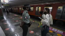 Seorang pelanggan meminta informasi kepada petugas Garda Nasional Meksiko di stasiun kereta bawah tanah kota di Mexico City, Kamis (12/1/2023). Wali Kota Mexico City mengatakan lebih dari 6 ribu petugas Garda Nasional akan ditempatkan di sistem kereta bawah tanah kota setelah serangkaian kecelakaan yang menurut para pejabat bisa jadi karena sabotase. (AP Photo/Fernando Llano)