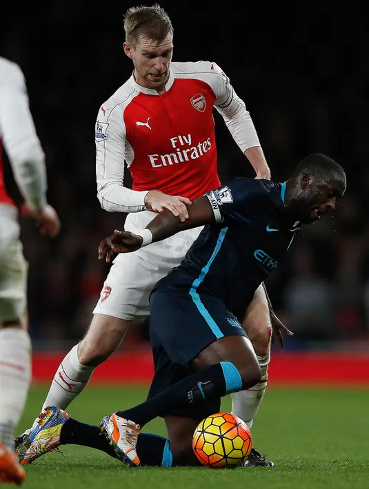 Gelandang Manchester City, Yaya Toure (kanan) berusaha membawa bola dari kawalan bek Arsenal, Per Mertesacker pada lanjutan liga Inggris di Stadion Emirates (21/12). Arsenal menang atas City dengan skor 2-1. (AFP PHOTO/ADRIAN DENNIS)