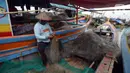 Seorang nelayan memperbaiki jaring di atas perahu yang bersandar di Dermaga Muara Angke, Jakarta, Selasa (19/2021). Memasuki musim pancaroba ditambah kencangnya angin, nelayan mengatakan hasil tangkapan ikan menjadi tidak menentu. (merdeka.com/Imam Buhori)