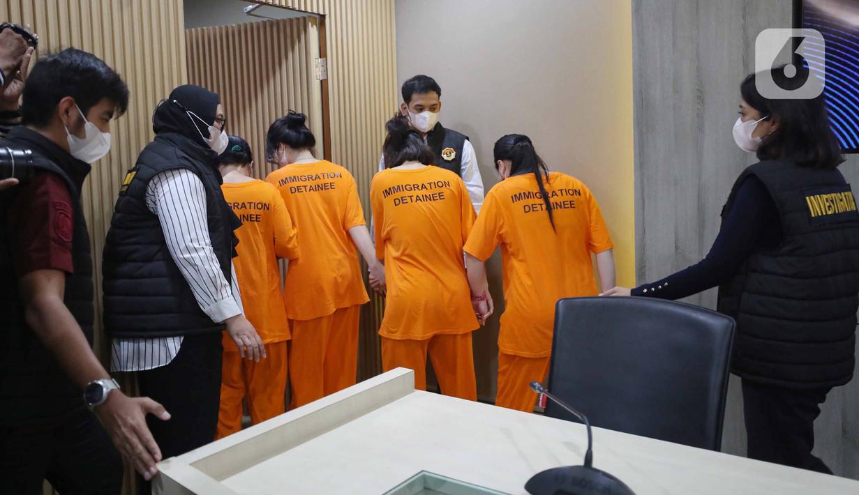 Petugas menggiring Warga Negara Asing (WNA) asal Vietnam yang tertangkap usai rilis penangkapan pelanggar izin tinggal di kantor Direktorat Jenderal (Ditjen) Imigrasi, Jakarta, Jumat (10/1/2025). (Liputan6.com/Angga Yuniar)