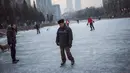 Aksi seorang pria saat bermain ice skating atau seluncur es di atas sungai yang telah membeku di Beijing, Jumat (1/1). Semenjak membeku, sungai di Beijing ini menjadi objek wisata dadakan yang banyak diminati wisatawan.  (AFP/Fred Dufour)