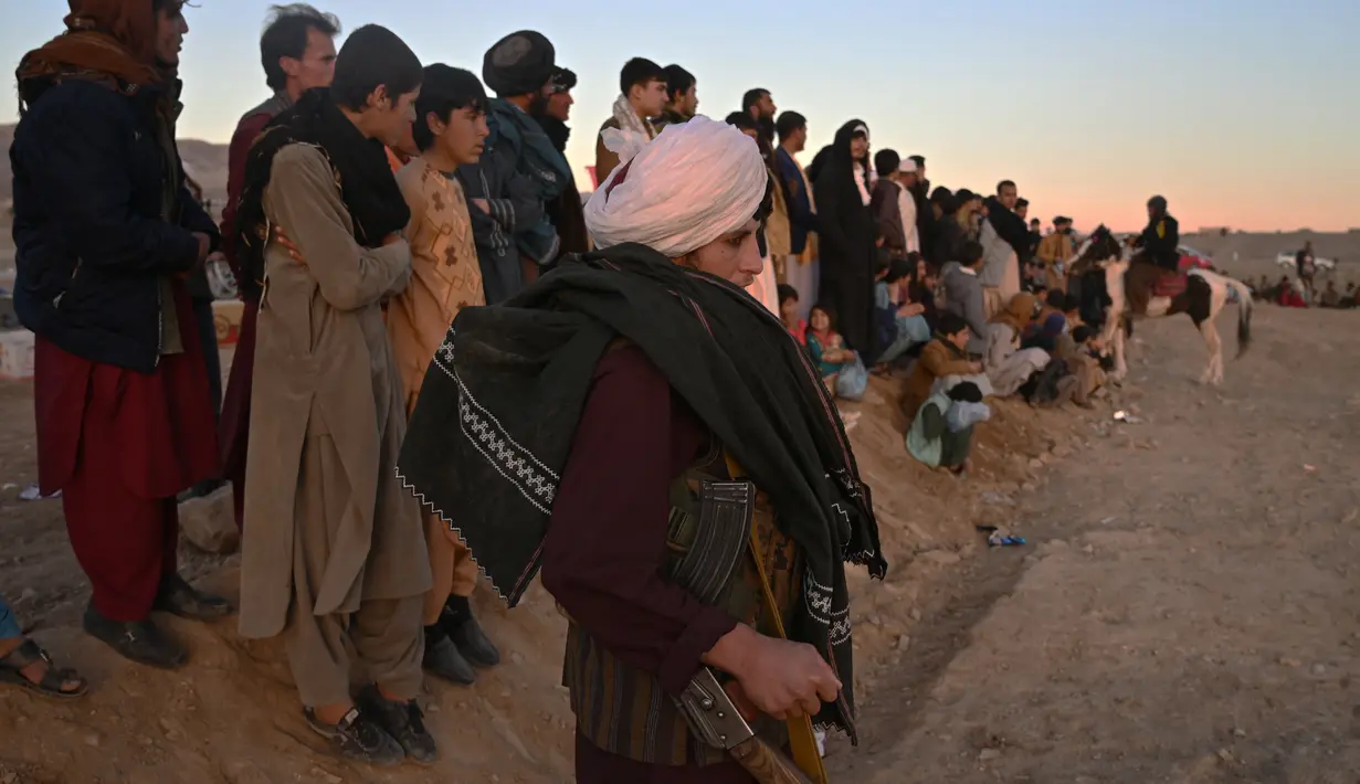 Seorang pejuang Taliban menonton buzkashi, olahraga Asia Tengah di mana para pemain berkuda berusaha memperebutkan bangkai hewan yang dipenggal kepalanya ke gawang di Herat, Afghanistan (4/2/2022). (AFP/Wakil Kohsar)