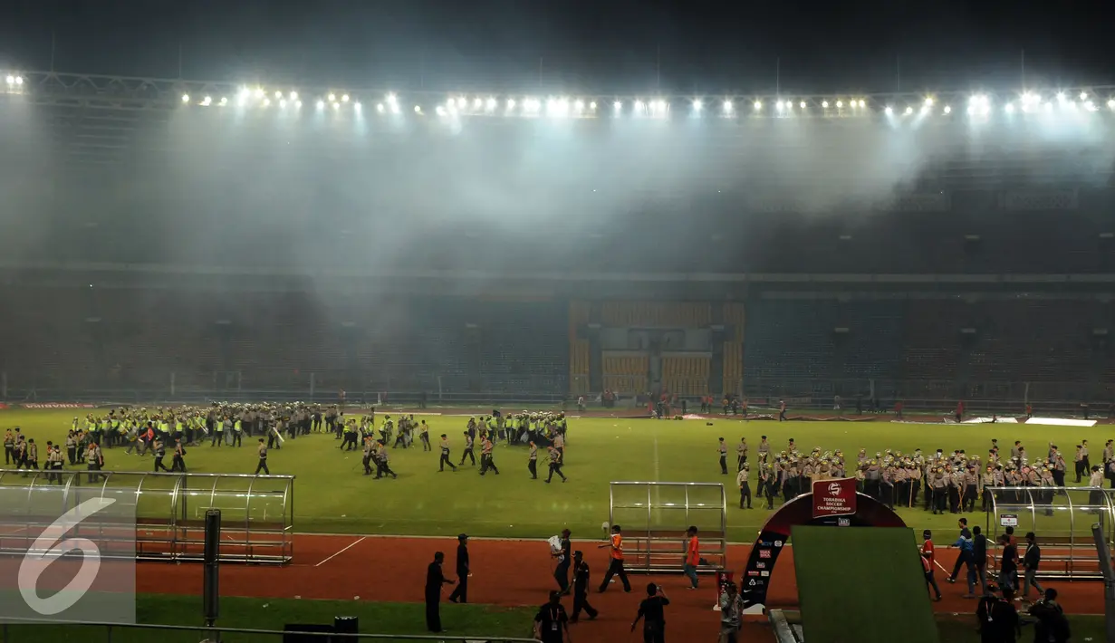 Petugas kepolisian menguasai lapangan setelah terlibat bentrok dengan suporter saat laga Persija melawan Sriwijaya FC di Stadion GBK Jakarta, Jumat (24/6). Laga dihentikan di menit 81.(Liputan6.com/Helmi Fithriansyah)