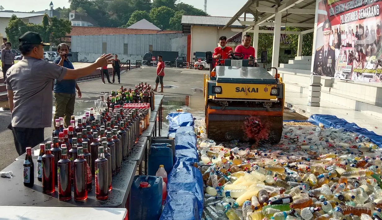 Petugas dengan alat berat menghancurkan botol minuman keras (miras) saat pemusnahan Miras dan barang bukti narkotika di Mapolrestabes Semarang, Jumat (20/12/2019). Pemusnahan barang bukti narkoba berupa sabu, inex dan pil koplo serta 5450 botol dan 140 liter ciu. (Liputan6.com/Gholib)